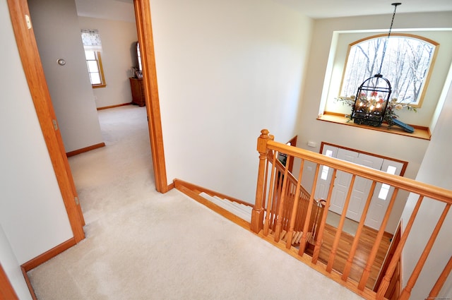 stairway featuring a notable chandelier, carpet flooring, and baseboards