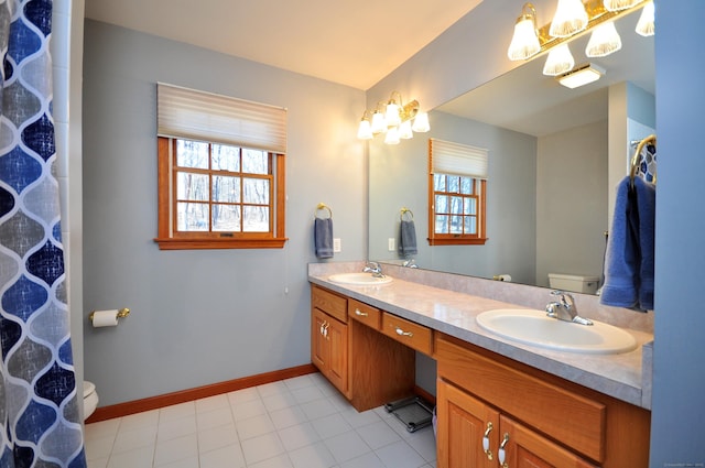 full bath featuring double vanity, toilet, baseboards, and a sink