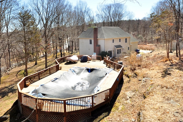 back of property featuring a wooded view and a deck