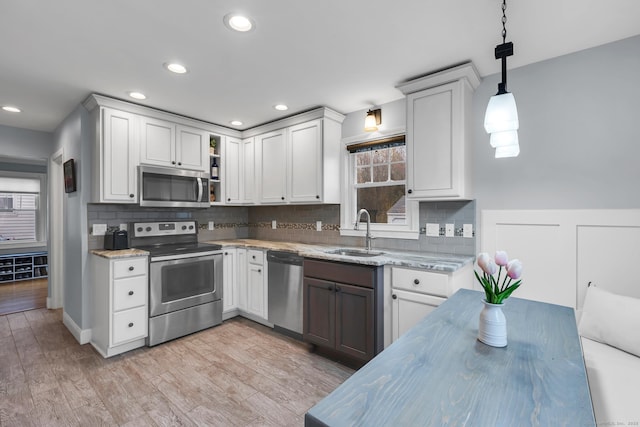 kitchen featuring a sink, decorative backsplash, light stone countertops, and stainless steel appliances