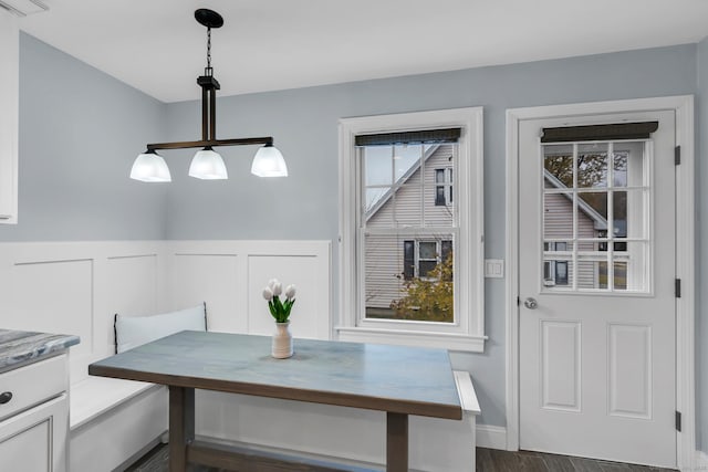 dining area featuring a wainscoted wall, visible vents, breakfast area, a decorative wall, and dark wood-style flooring