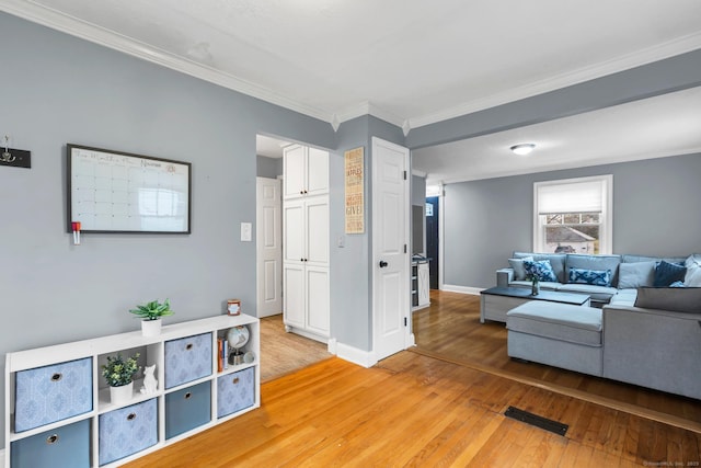 living area with mail area, baseboards, light wood-style flooring, and ornamental molding