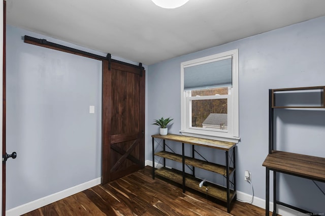 interior space featuring a barn door, dark wood-style floors, and baseboards