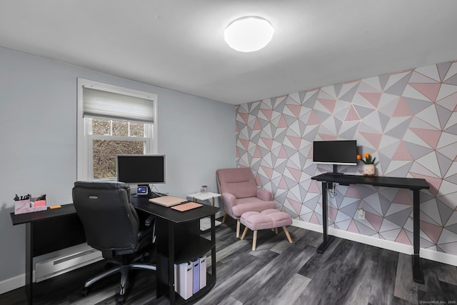 home office with a baseboard heating unit, dark wood-style floors, wallpapered walls, baseboards, and an accent wall