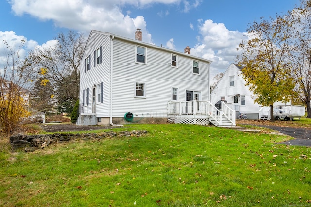 back of house with a deck, a yard, and a chimney