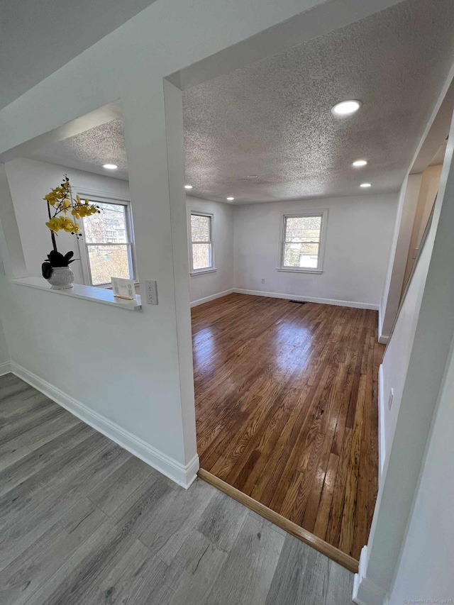 interior space with recessed lighting, baseboards, a textured ceiling, and wood finished floors