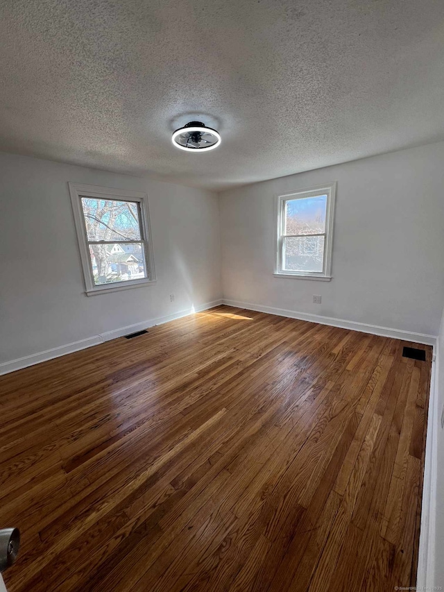 empty room featuring baseboards, visible vents, and dark wood-style flooring