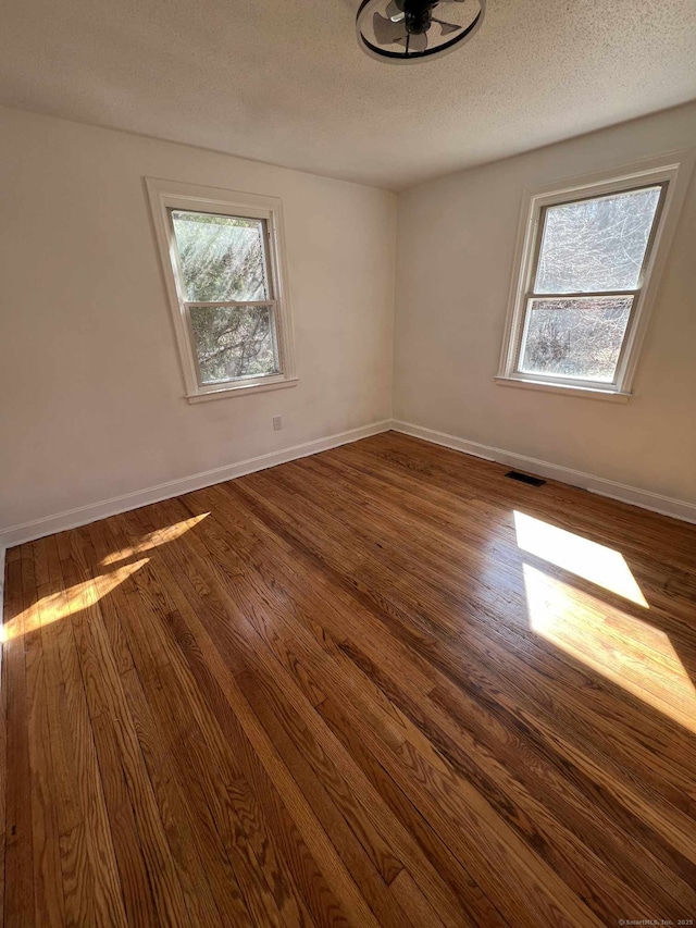 spare room with visible vents, dark wood-style flooring, and a textured ceiling