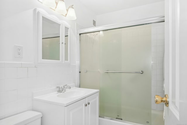 bathroom featuring vanity, a shower stall, toilet, and tile walls