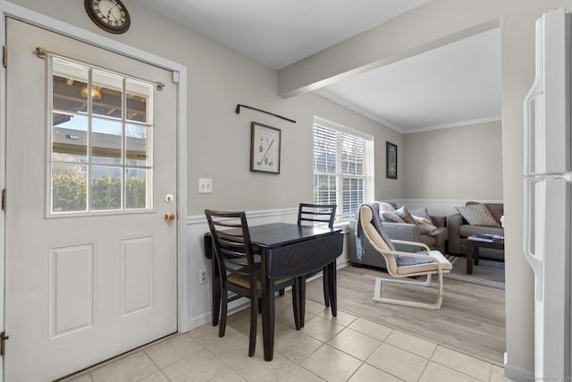 dining space featuring light tile patterned floors, beamed ceiling, and crown molding