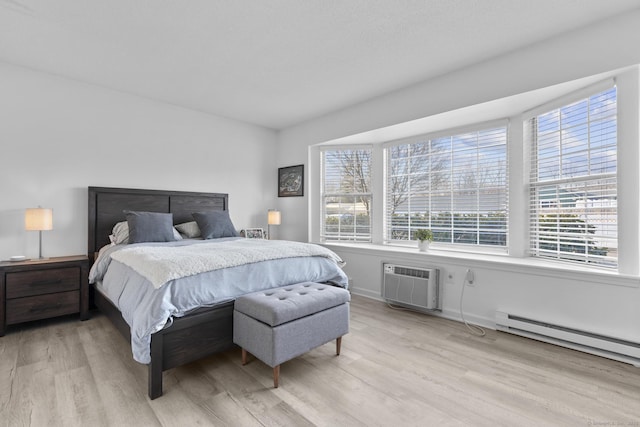 bedroom with light wood-style flooring, a wall mounted AC, and a baseboard radiator