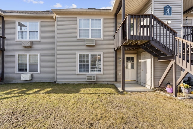 back of property featuring stairway, an AC wall unit, and a yard