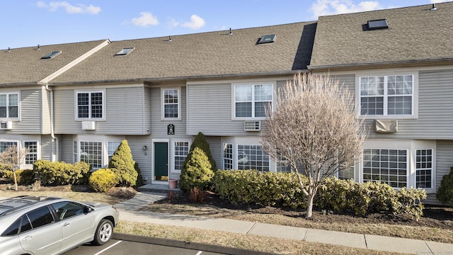 view of property featuring uncovered parking and a shingled roof