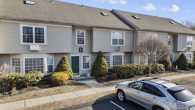 multi unit property featuring roof with shingles and uncovered parking