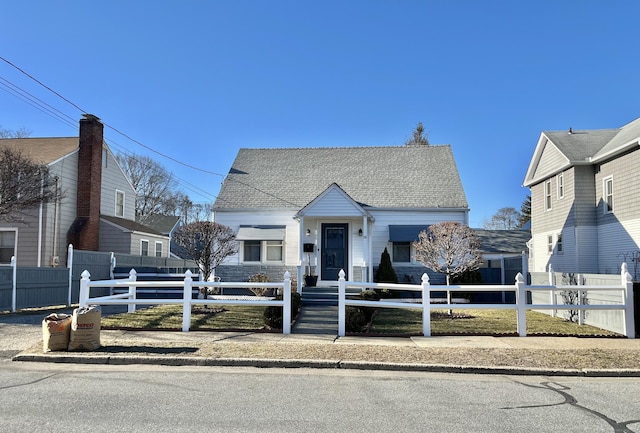 bungalow featuring a fenced front yard and roof with shingles