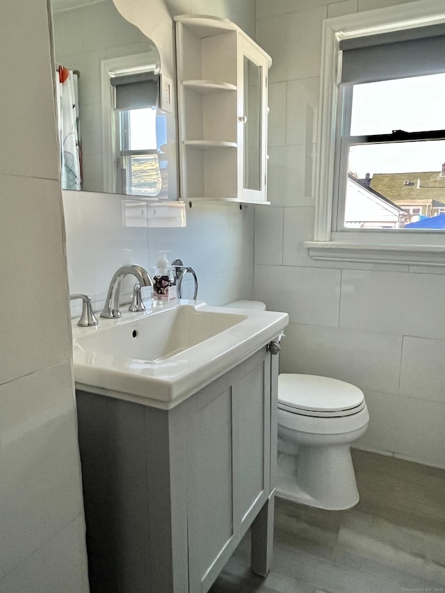 full bathroom featuring toilet, vanity, a shower with curtain, wood finished floors, and tile walls