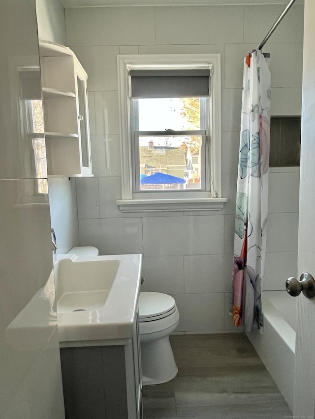 bathroom featuring shower / bath combo with shower curtain, toilet, wood finished floors, tile walls, and vanity