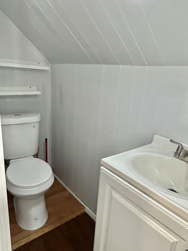 bathroom featuring toilet, wood finished floors, vanity, and vaulted ceiling