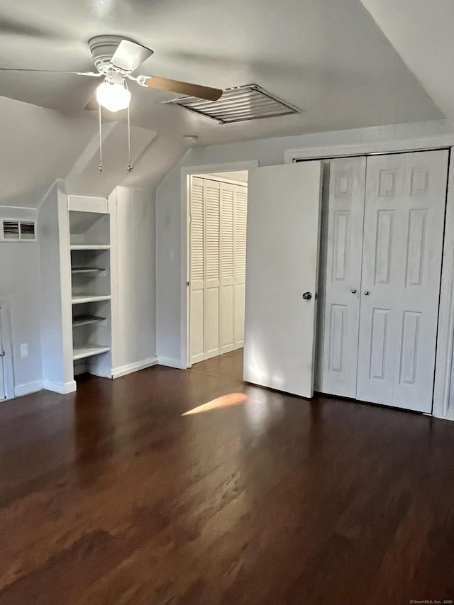 additional living space featuring visible vents, built in shelves, dark wood finished floors, vaulted ceiling, and a ceiling fan