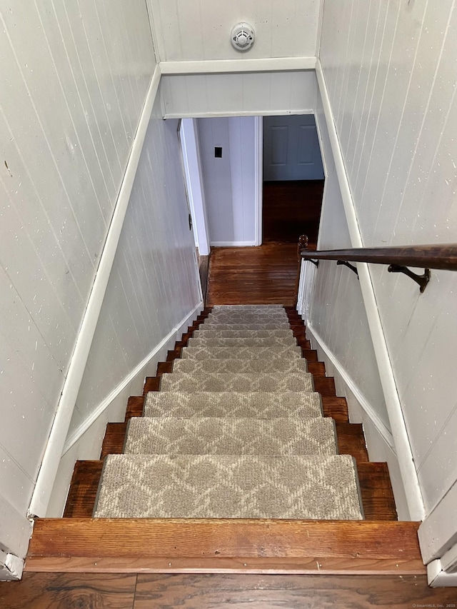 staircase with visible vents, wooden walls, and wood finished floors