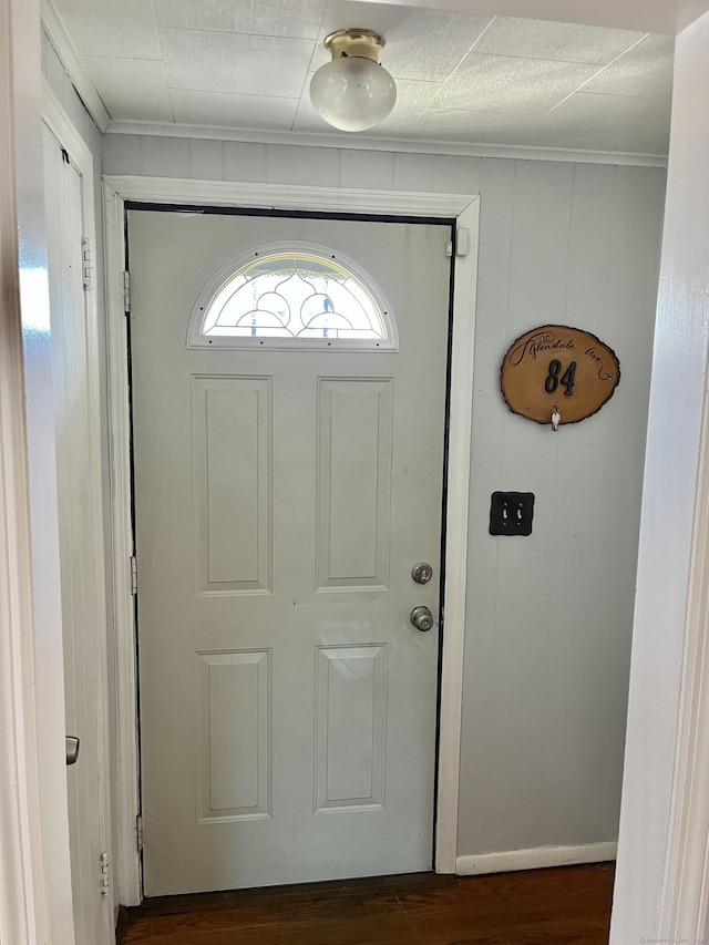 foyer featuring dark wood finished floors, crown molding, and baseboards