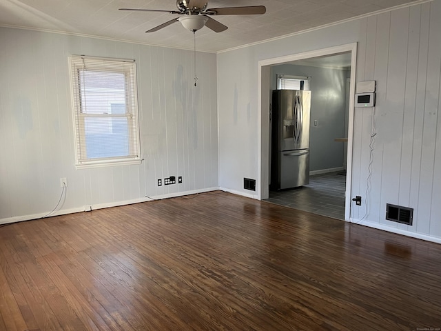 empty room with visible vents, baseboards, ornamental molding, wood finished floors, and a ceiling fan