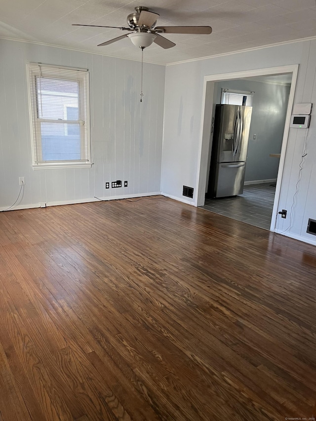 empty room featuring baseboards, visible vents, dark wood-style flooring, ceiling fan, and ornamental molding