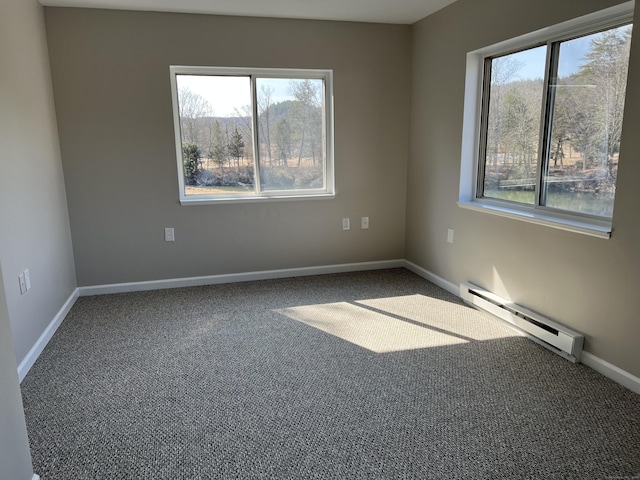 carpeted empty room featuring a healthy amount of sunlight, a baseboard heating unit, and baseboards