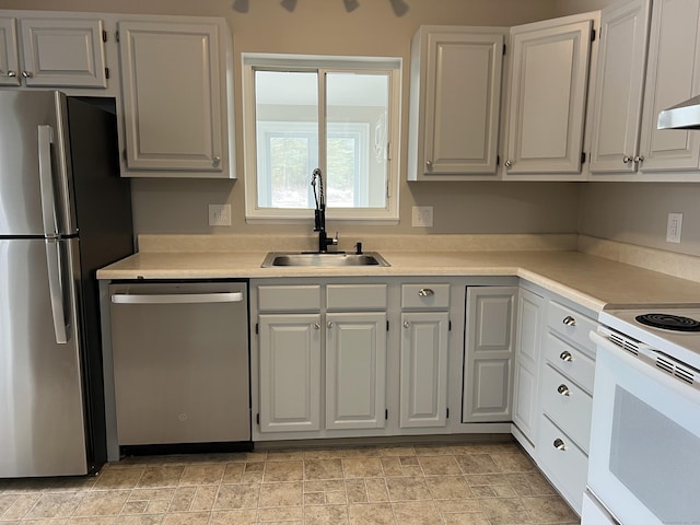 kitchen featuring stone finish flooring, light countertops, appliances with stainless steel finishes, white cabinets, and a sink