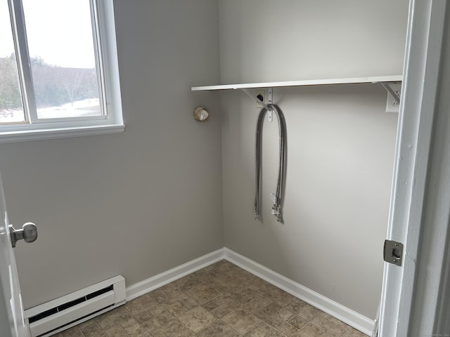 laundry room with a baseboard heating unit, laundry area, and baseboards