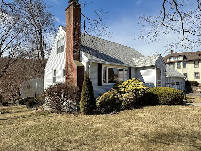 view of home's exterior featuring a lawn, a chimney, and a shingled roof