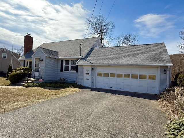 view of front facade featuring driveway, a shingled roof, and a garage