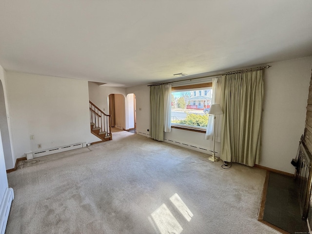 unfurnished living room featuring a baseboard heating unit, stairs, arched walkways, and light carpet