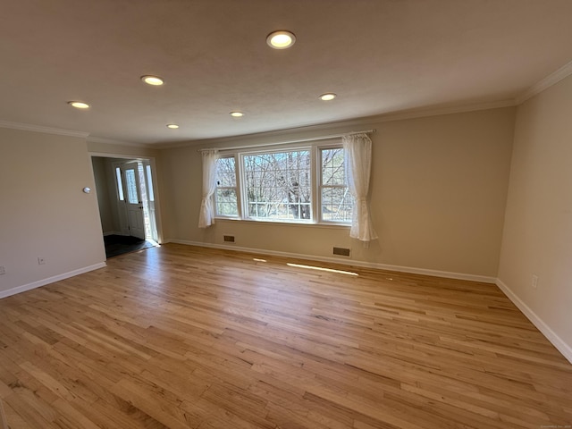 unfurnished room featuring light wood finished floors, visible vents, baseboards, and ornamental molding