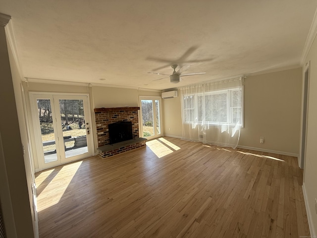 unfurnished living room featuring a wall mounted air conditioner, wood finished floors, a fireplace, crown molding, and ceiling fan