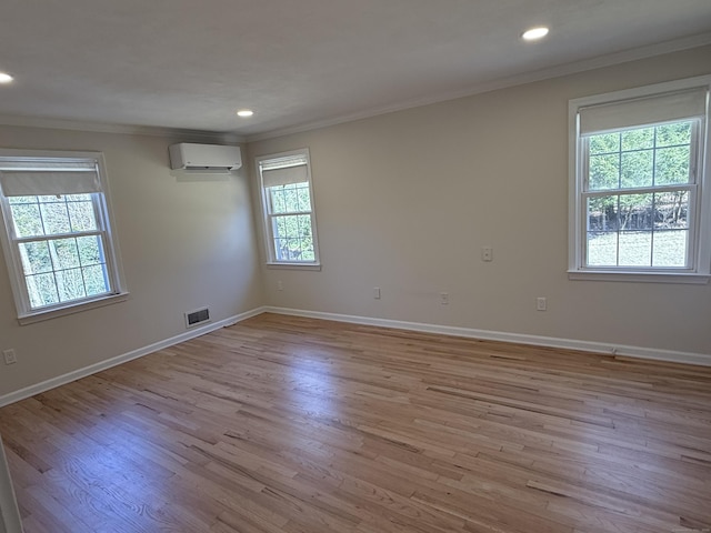 unfurnished room with a wall unit AC, light wood-style floors, visible vents, and ornamental molding