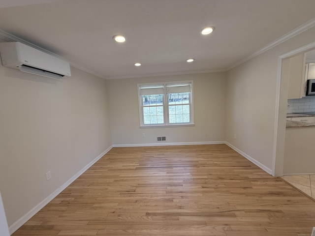 unfurnished room with a wall unit AC, baseboards, visible vents, light wood-style flooring, and ornamental molding