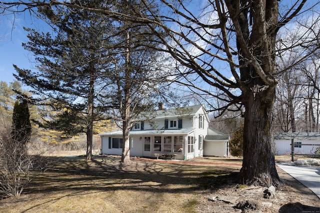 view of front of home featuring a front yard, a chimney, and a sunroom