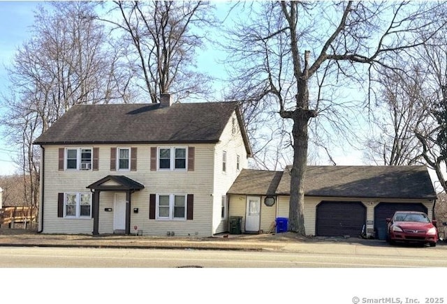 colonial home featuring an attached garage and a chimney