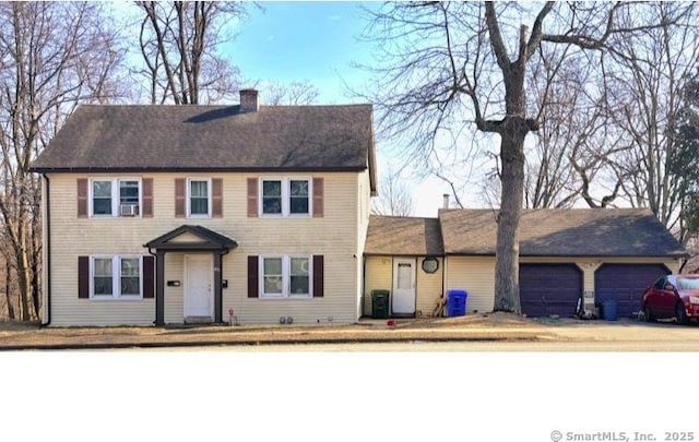 colonial-style house featuring a chimney and a garage