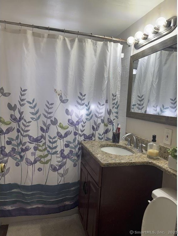 full bath with toilet, vanity, and a shower with curtain