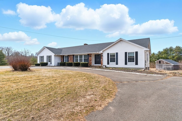 ranch-style house featuring aphalt driveway, brick siding, and a front yard