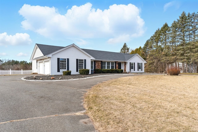 single story home with a front lawn, an attached garage, fence, and driveway