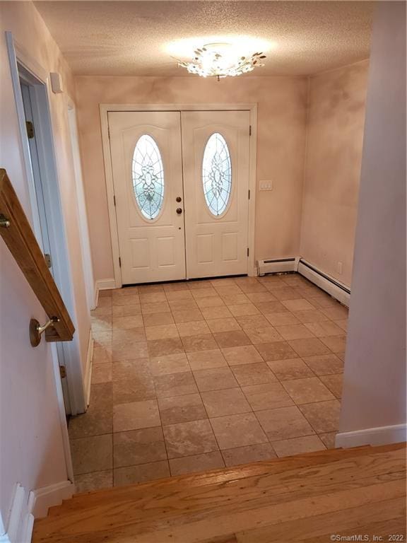 foyer entrance featuring a textured ceiling and baseboards