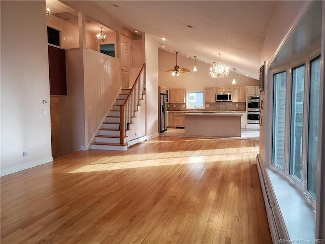 unfurnished living room featuring light wood finished floors, a baseboard radiator, stairs, ceiling fan with notable chandelier, and baseboard heating