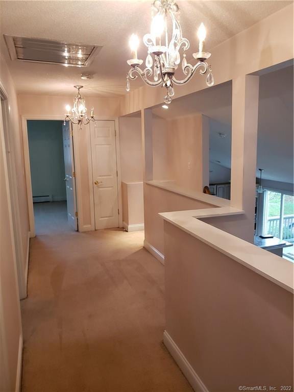 hallway with a baseboard radiator, light carpet, baseboards, and a chandelier