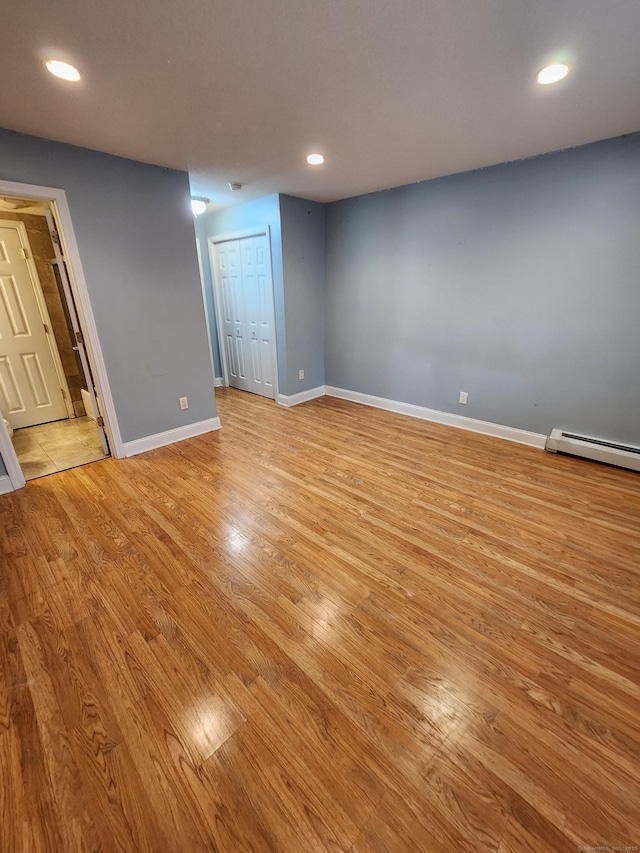 unfurnished room featuring recessed lighting, baseboards, light wood finished floors, and a baseboard radiator