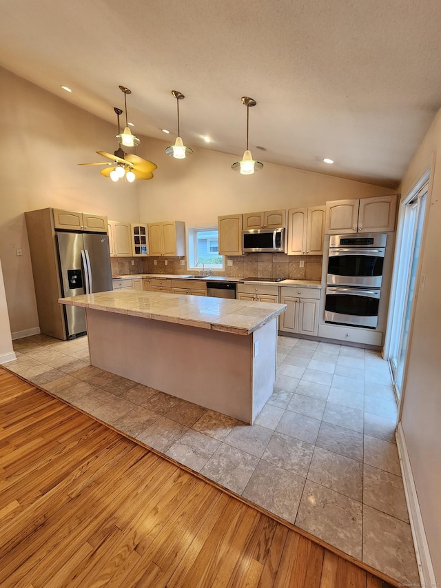 kitchen featuring light wood-style floors, stainless steel appliances, backsplash, and a center island