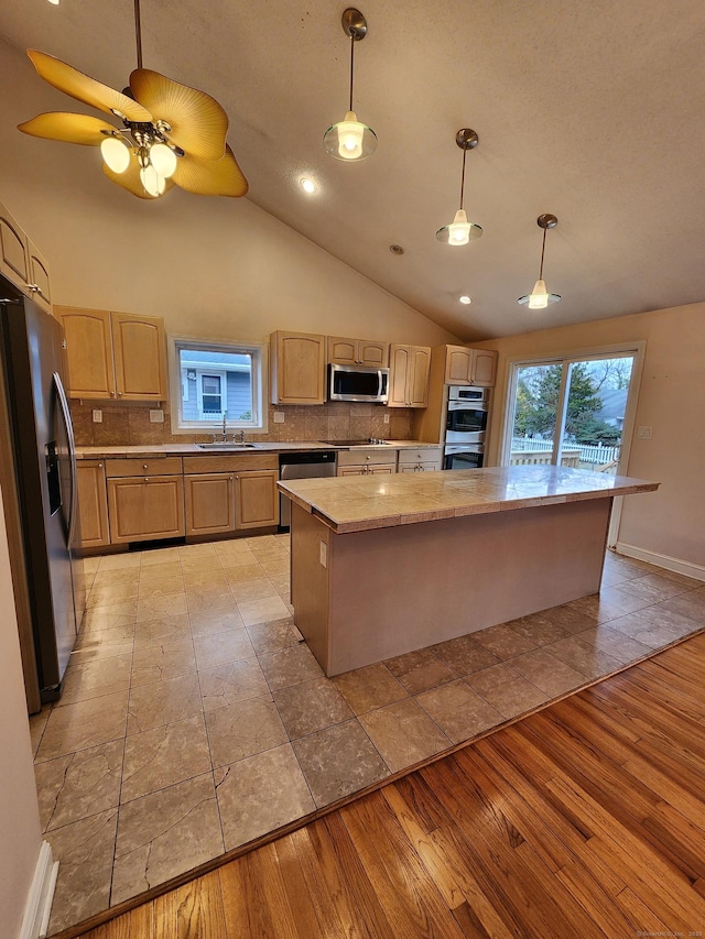 kitchen with light wood finished floors, tasteful backsplash, appliances with stainless steel finishes, and a sink