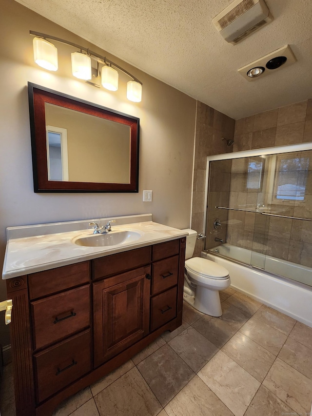 full bath featuring vanity, visible vents, shower / bath combination with glass door, a textured ceiling, and toilet